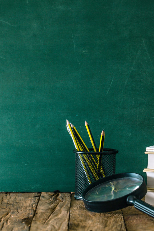a couple of buckets with pens in them next to a chalkboard