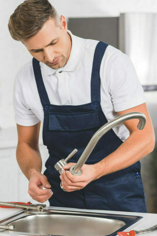 adult repairman taking off kitchen faucet for repairing