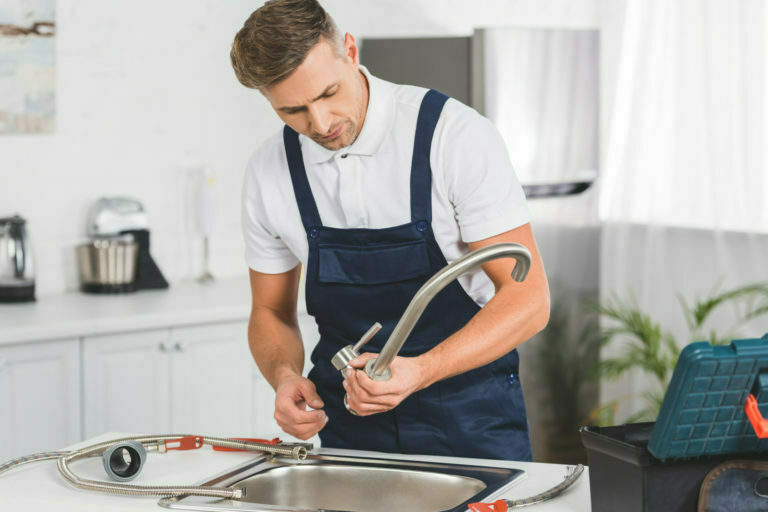 adult repairman taking off kitchen faucet for repairing